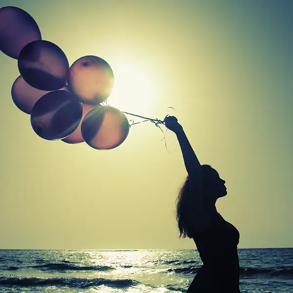 Schwebende Luftballons gehalten von einer Frau